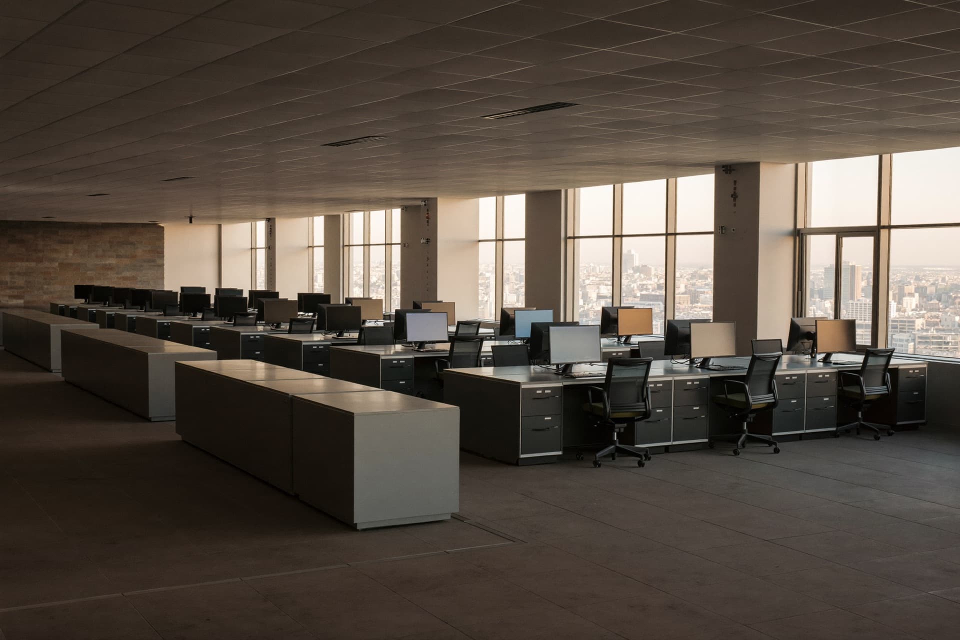 A capital markets trading floor after hours, rows of desks under linear lights.